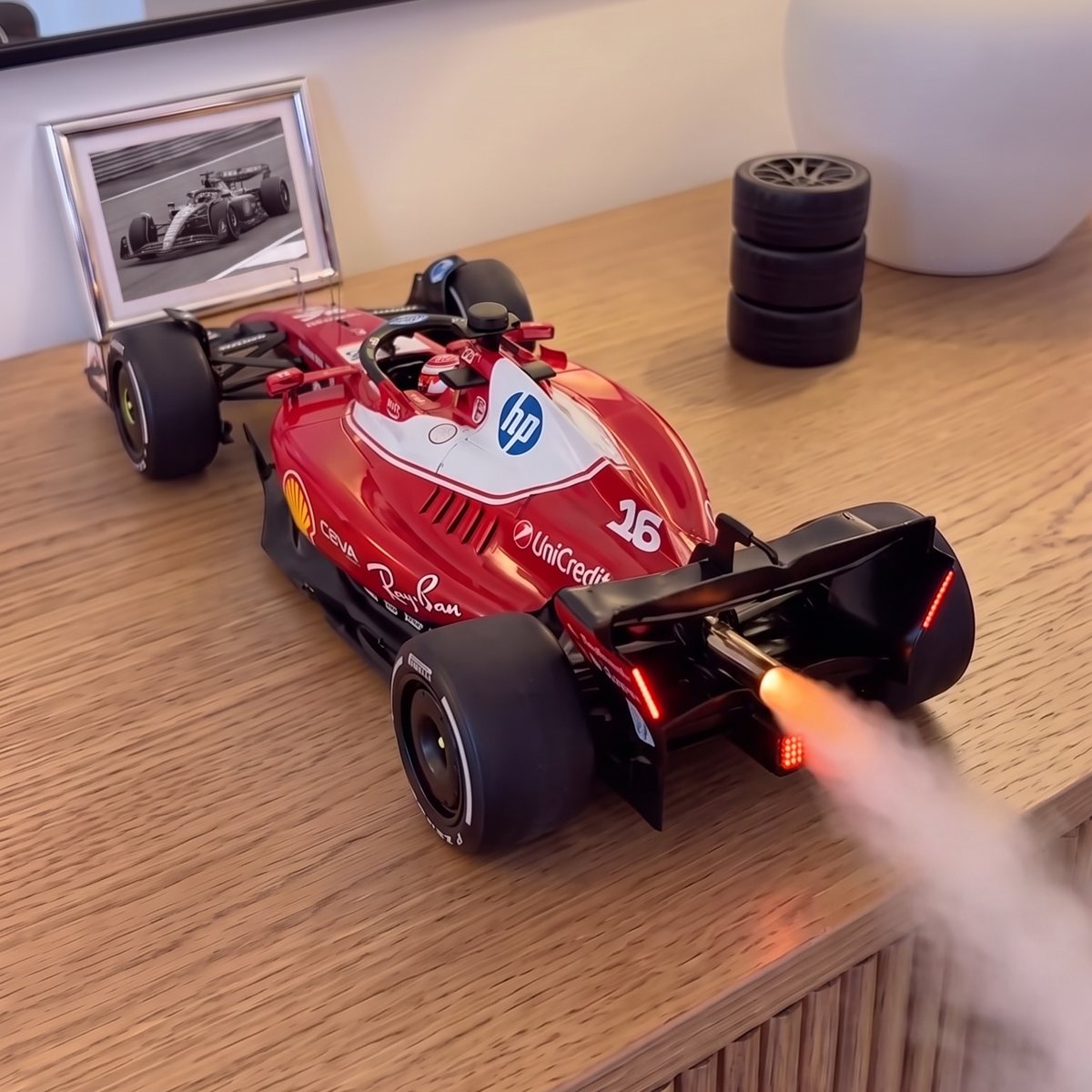 GRIDMIST F1 car mist diffuser on a sideboard, mist rolling from the glowing exhaust
